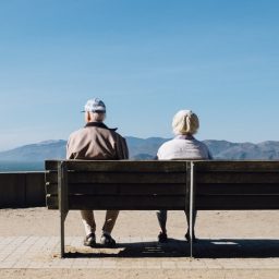 Two elderly seniors sitting on a bench