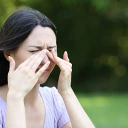 Women experiencing allergy symptoms outdoors.