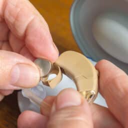 Woman changes the battery in her hearing aids.