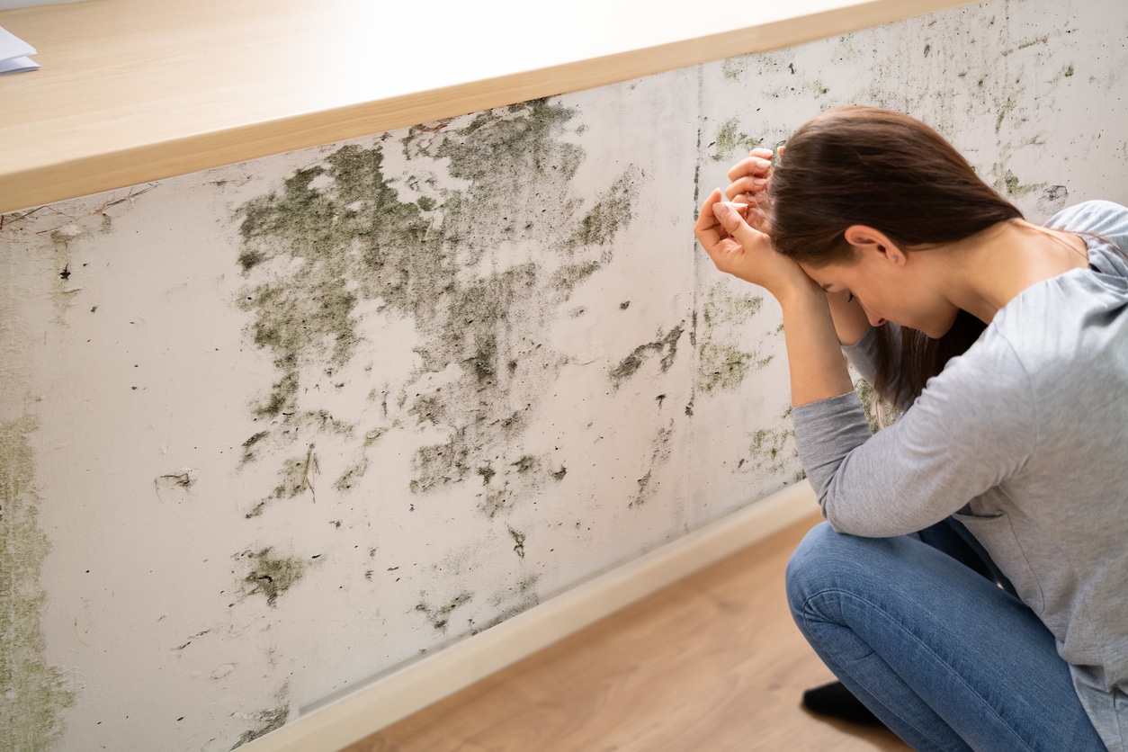 Woman frustrated at mold on the wall.