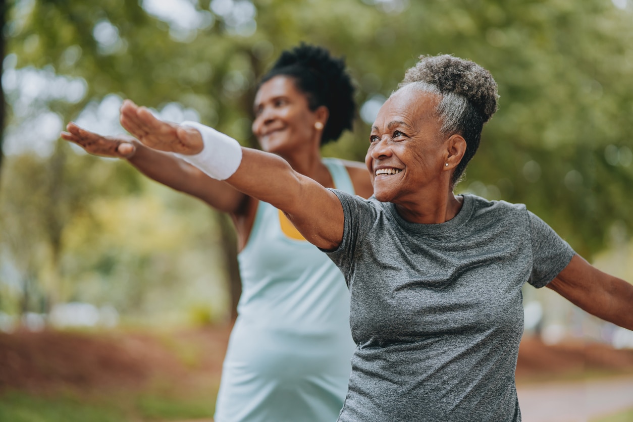 Two women doing warrior pose yoga in a park