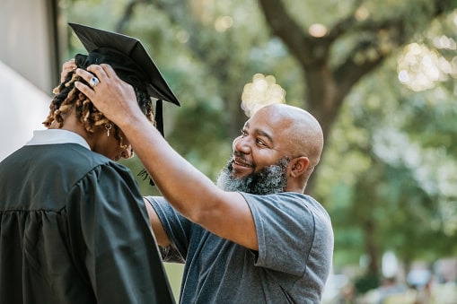 Proud father adjusts his kid's graduation cap before the graduation ceremony.